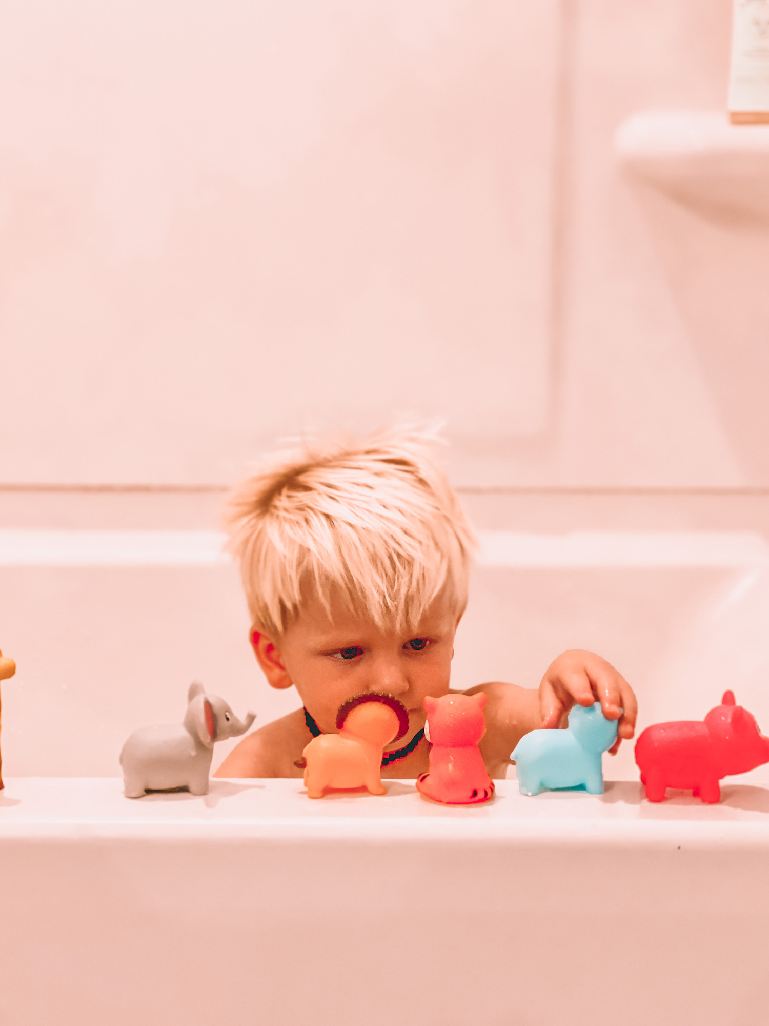 Little boy lining up toys on bath tub